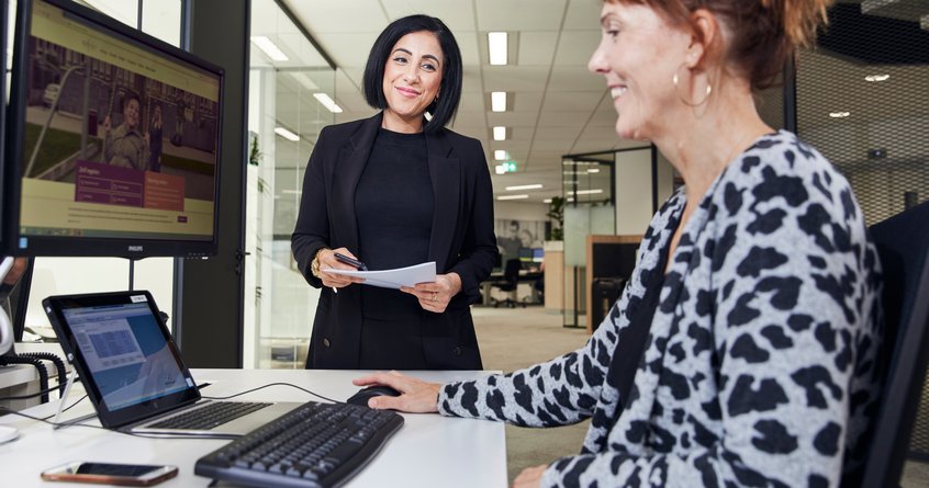 Medewerker helpt klant aan de balie achter een computer